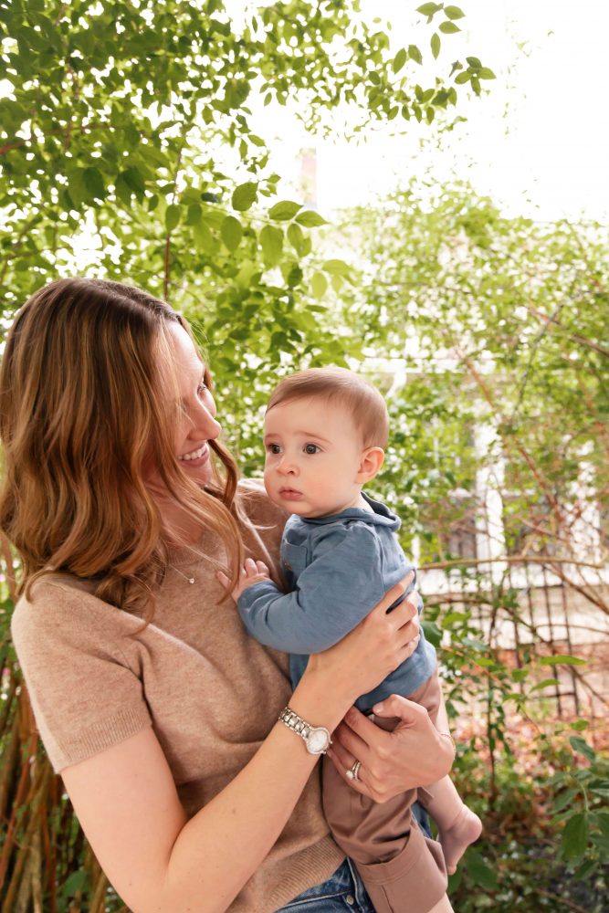 A happy mom holding her young son on the front porch during a lifestyle family photo session.