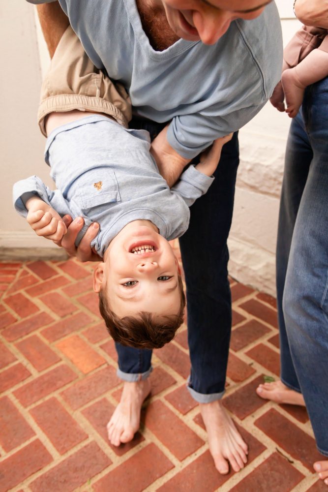 Natural family portraits featuring a father playing with his toddler and a mother cuddling their baby.